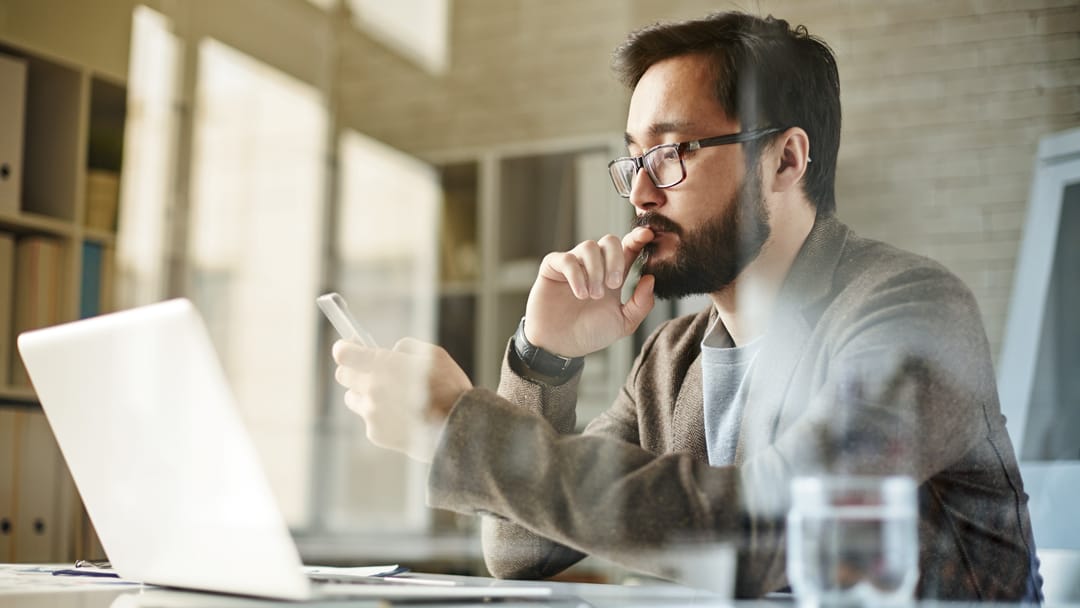 man working on phone at desk